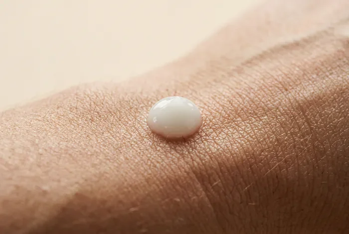 Tatouage qui croûte au bout de 2 jours : causes et soins Vue macro minimaliste d'une crème cicatrisante sur une peau tatouée